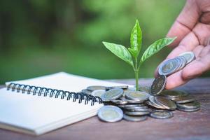 Hands of businessmen giving coins to trees growing on coins. photo