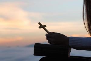 silueta de mujer joven rezando con cruces y biblias al amanecer, fondo del concepto de religión cristiana. foto