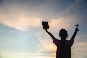 la mano humana sostiene la cruz y la biblia, la adoración, los pecados y la oración, el concepto religioso, la terapia de la eucaristía bendiga a dios ayudando a arrepentirse la pascua católica prestó la mente orar. foto