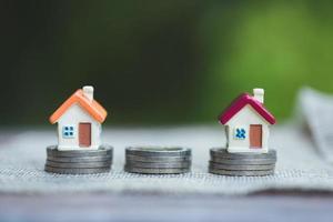 Minature houses resting on coin stacks, concept for property ladder, mortgage and real estate investment photo