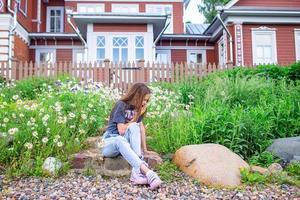 Little blonde girl pick flowers in a meadow full of chamomiles photo