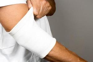Man wearing an elastic type ace bandage on his elbow photo