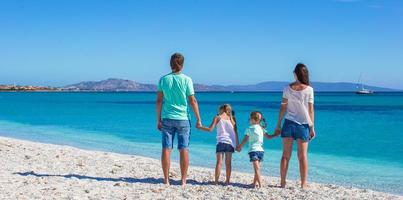 vista posterior de la familia con dos niños en vacaciones tropicales foto