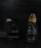 par de zapatos clásicos masculinos negros sobre fondo negro. zapatos polvorientos foto