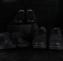 par de zapatos clásicos masculinos negros sobre fondo negro. zapatos polvorientos foto