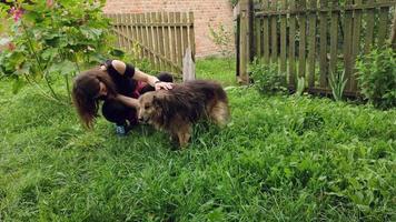 Girl petting an old sick street dog in the garden. video