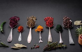 Several types of spices in metal spoons paprika, tomatoes, curry, beets, cumin, turmeric, fennel, spirulina photo