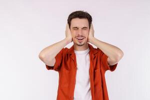 Portrait of attractive man close ears from noisy neighbours, looking up and shouting annoyed, hearing loud music on isolated background. photo