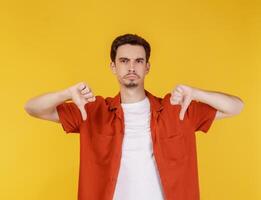 Portrait of young man shows sign of dislike, looks with negative expression and disapproval on isolated background photo