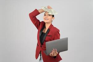 Young beautiful woman in formal clothing for officer hold banknote and laptop photo