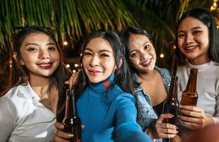 Portrait of Happy Asian friends having dinner party together - Young people toasting beer glasses dinner outdoor  - People, food, drink lifestyle, new year celebration concept. photo