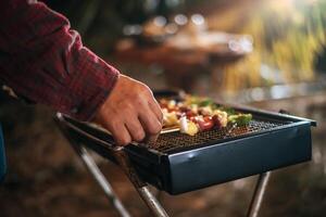 Close up hand of Man cooking meat on barbecue grill at new year party. Bar-B-Q or BBQ on traditional stove. Night Party, people and celebration concept. photo