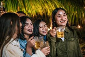 retrato de felices amigos asiáticos cenando juntos - jóvenes brindando con vasos de cerveza cenando al aire libre - gente, comida, estilo de vida de bebida, concepto de celebración de año nuevo. foto