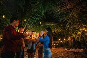 Portrait of Happy Asian friends having dinner party together - Young people toasting beer glasses dinner outdoor  - People, food, drink lifestyle, new year celebration concept. photo