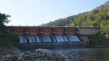 cenário da manhã na represa de kiew lom, lampang, tailândia. barragem hidrelétrica, comporta com água fluindo pelo portão. barragem com central hidroeléctrica e rega. video