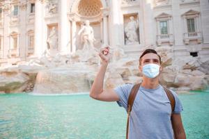 Young man near fountain Fontana di Trevi with coins in hands photo