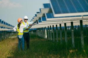 Asian Young Inspector Engineer man and female colleague checking operation in solar farm photo