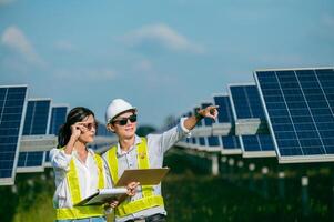 joven inspector asiático ingeniero hombre y mujer caminando comprobando la operación en una granja solar foto