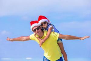 Little girl and happy father in Santa Hats enjoy Christmas vacation photo