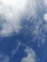 White clouds in the blue sky. Beautiful bright blue background. Light cloudy, good weather. Curly clouds on a sunny day. photo