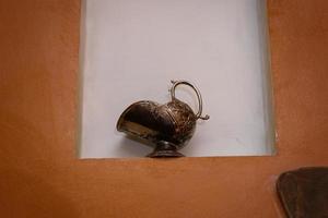 jarra de metal vintage, de pie en una pared de nicho foto