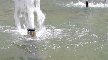 respingo ou jato de água em uma fonte em câmera lenta. close-up de uma fonte da cidade em um dia quente de verão. gotas de água e salpicos brilham ao sol. pressão da água. fontes dançantes. video