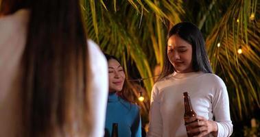 filmmaterial von glücklichen asiatischen freunden, die zusammen eine dinnerparty haben - junge leute, die biergläser zum abendessen im freien anstoßen - menschen, essen, trinken, lebensstil, neujahrsfeierkonzept.