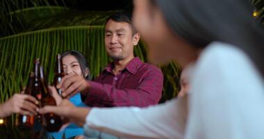 des images d'amis asiatiques heureux en train de dîner ensemble - des jeunes assis à la table du bar en train de griller une bouteille de bière en plein air - les gens, la nourriture, le mode de vie des boissons, le concept de célébration du nouvel an. video