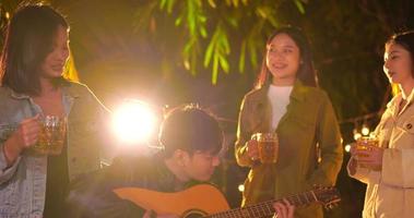 Footage of Happy Asian group of friends having fun to music dining and drinking together outdoor - Happy friends group toasting beers  - People, food, drink lifestyle, new year celebration concept. video