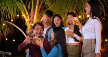 imágenes de amigos asiáticos felices cenando juntos - jóvenes sentados en la mesa del bar brindando vasos de cerveza cenando al aire libre - gente, comida, estilo de vida de bebida, concepto de celebración de año nuevo. video