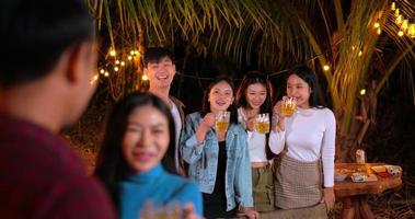 metraggio di contento asiatico amici avendo cena festa insieme - giovane persone seduta a bar tavolo tostatura birra bicchieri cena all'aperto - le persone, cibo, bevanda stile di vita, nuovo anno celebrazione concetto. video