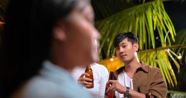 Aufnahmen von glücklichen asiatischen Freunden, die zusammen eine Dinnerparty haben - junge Leute, die am Bartisch sitzen und Bierflaschenessen im Freien anstoßen - Menschen, Essen, Trinken, Lebensstil, Neujahrsfeierkonzept.