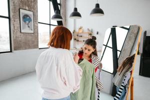 Happy beautiful young woman choosing clothes with girlfriend. photo