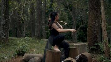 A Woman chilling in the jungle by squat between the tree in the forest video