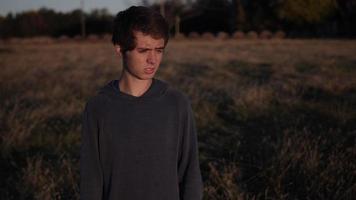 Junger Mann, Teenager blinzelt, um den Sonnenuntergang zu beobachten video