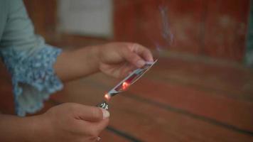 A Woman burning a photo frame with gasoline in front of the house with brown floor video