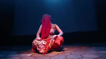 A Scarf dancer uses the red clothes to cover her face while moving with her body video