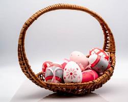 wicker basket with colored easter eggs, on a white background in the period of easter 2023 photo