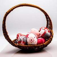 wicker basket with colored easter eggs, on a white background in the period of easter 2023 photo