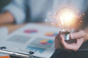 analyst holding a light bulb, business statistics chart report concept ,to analyze and improve corporate strategies, Manage financial and marketing documents, modern business growth data photo