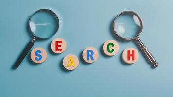 Magnifying glass and wooden block on blue background,Keyword search concept to find information from online websites, optimization analysis tools, SEO ,searching for information in the internet world photo