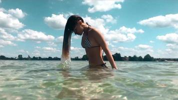 Charming young girl in swimsuit having fun in the sea in the summer time video