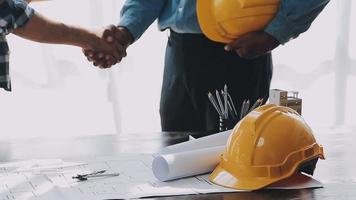 concepto de construcción y estructura de reunión de ingenieros o arquitectos para el proyecto que trabaja con socios y herramientas de ingeniería en la construcción de modelos y planos en el lugar de trabajo, contrato para ambas empresas. video