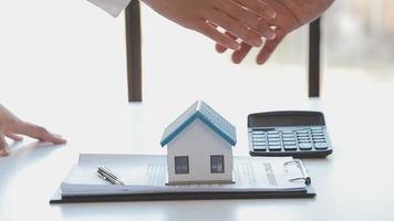 el agente de corretaje de bienes raíces entrega una muestra de una casa modelo al cliente, un contrato de préstamo hipotecario que arrienda y compra una casa y contrata el concepto de seguro de hogar video