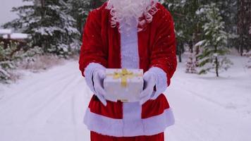 le père noël en plein air en hiver et la neige remettant une boîte cadeau à la main. présent, temps de donner des cadeaux, boîte d'emballage, livraison pour noël et nouvel an video