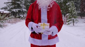 Papai Noel ao ar livre no inverno e neve, entregando a caixa de presente com a casa. presente de natal e ano novo, imóveis, compra, construção, realocação, hipoteca, reserva video