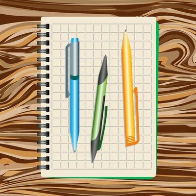 Notebook, blue pen, green pen and yellow pen on a wooden table