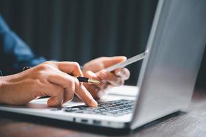 Closeup of businesswoman typing on laptop computer while sitting on table in office for design work, insert icons or business technology symbols. selective focus on hand. female online working on desk photo