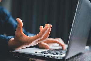 Closeup of businesswoman typing on laptop computer while sitting on table in office for design work, insert icons or business technology symbols. selective focus on hand. female online working on desk photo