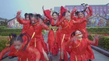 A Group of Asian teenagers dancing a hip-hop dance in red Chinese dress inside the temple video